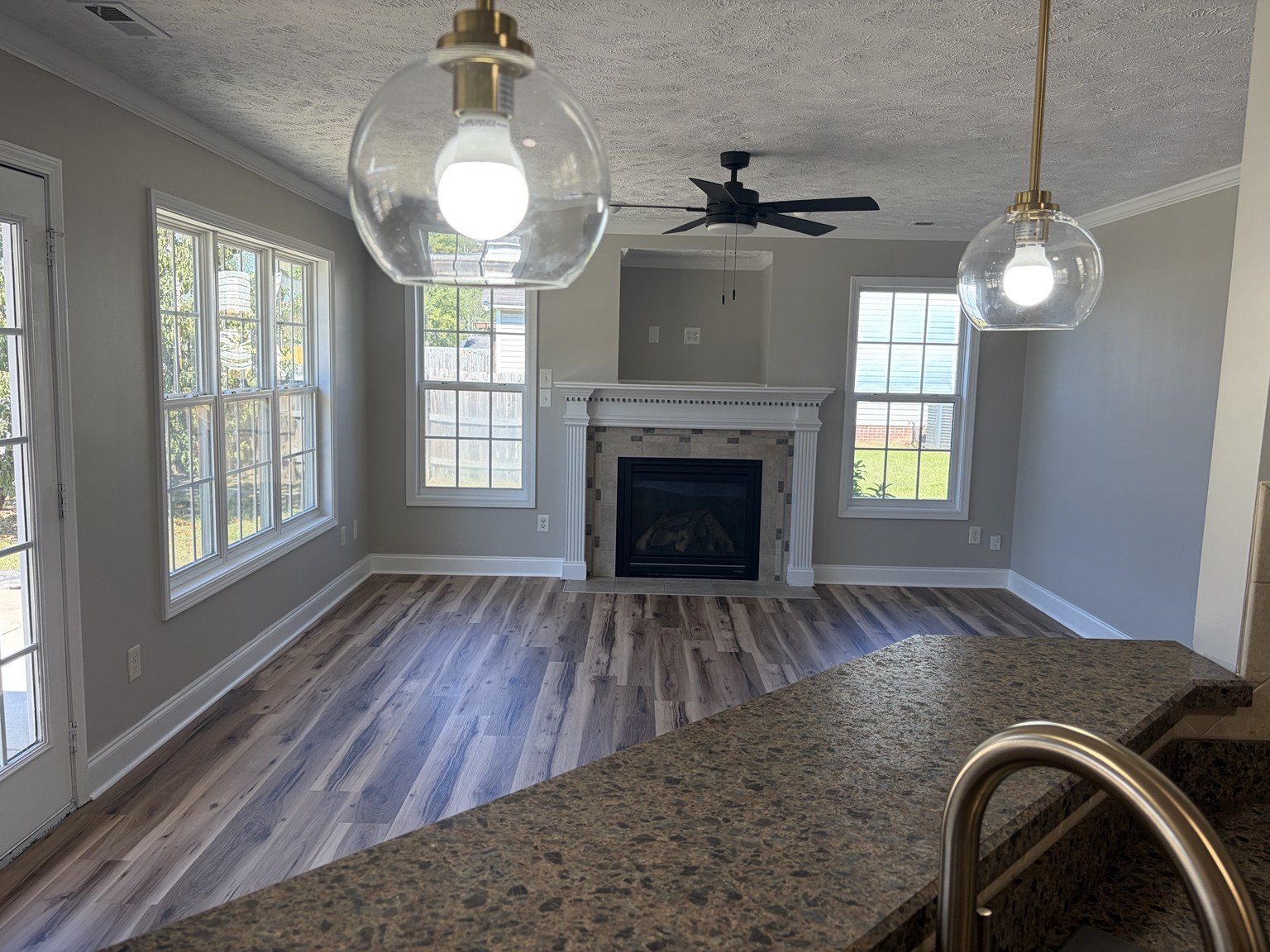 View from the kitchen toward a living area with windows and a fireplace
